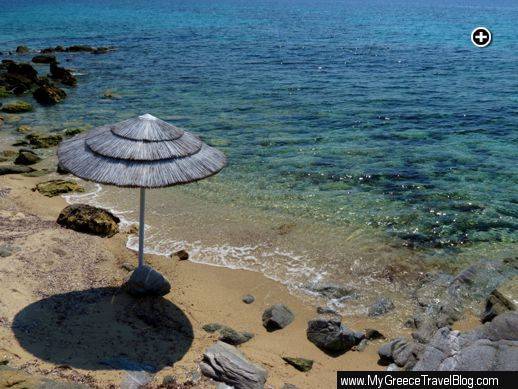 An umbrella casts its shadow on a sandy cove at Agios Ioannis beach on Mykonos