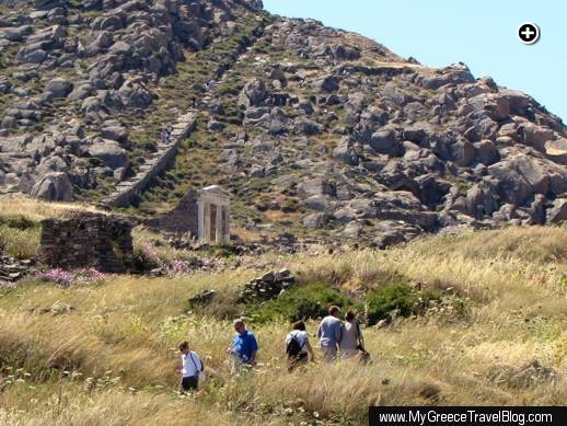 Tourists walk a path below the Temple of Isis (center left) while other Delos island visitors climb stairs to the summit of Mt Kynthos (upper left)