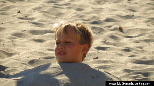 little boy buried in sand at Mikri Vigla beach 