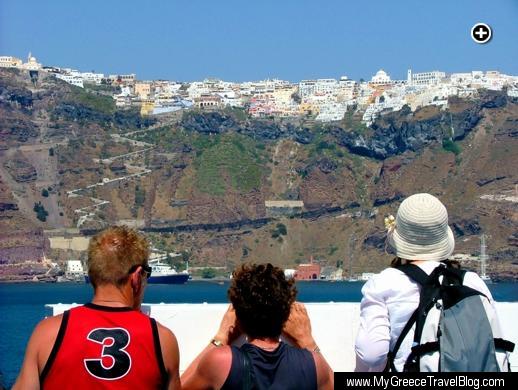 Ferry passengers look up at Fira village as their ship passes the caldera en route to the Santorini port