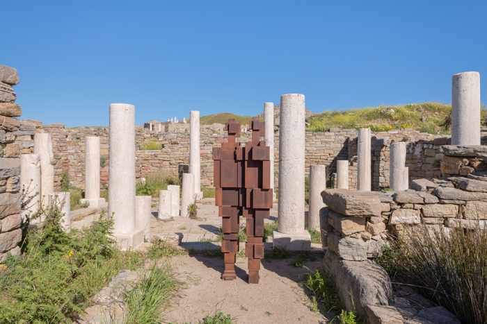 Photograph of an Antony Gormley iron sculpture displayed among the ruins on Delos island